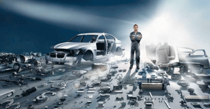 A veteran in a jumpsuit stands confidently beside an almost completely disassembled car, surrounded by various parts and components spread out on the ground, showcasing his skillful resettlement into civvy street.