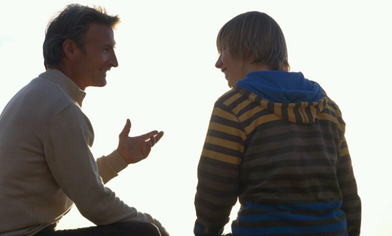 A veteran and a younger person sit outdoors, facing each other against a bright sky, engaged in conversation about the transition to civvy street.