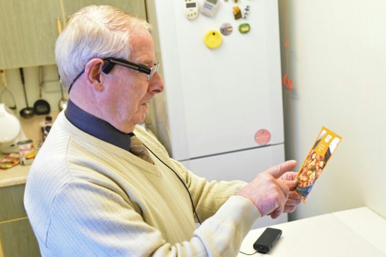 A veteran with glasses carefully reads a food package in the kitchen, adjusting to life on Civvy Street. A fridge hums quietly in the background, a symbol of his new normal.