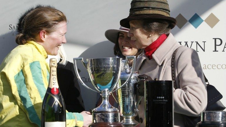 Two people exchange a handshake near a large trophy and champagne bottle at an event celebrating successful resettlement into Civvy Street, with another person in the background.
