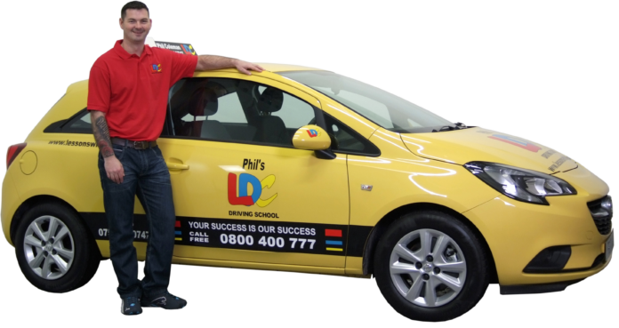 A veteran in a red shirt stands proudly next to a yellow car labeled 