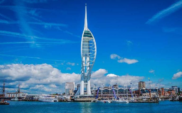 Spinnaker Tower in Portsmouth, UK, stands tall against a blue sky with scattered clouds; boats and the harbor bustle below. Nearby, veterans find new adventures on Civvy Street as they embrace resettlement and fresh beginnings.