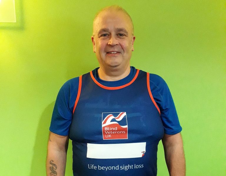 A veteran in a "Blind Veterans UK" running shirt stands against a bright green background, symbolizing his journey from civvy street to resettlement.