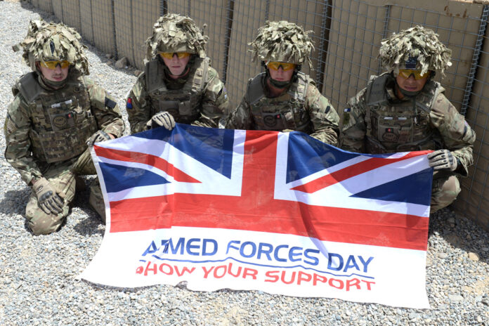 Four soldiers in camouflage gear proudly hold a 