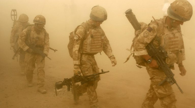 Four soldiers in desert camouflage navigate a sandy, dusty environment, carrying rifles and wearing helmets. Their mission accomplished; they prepare to transition back to Civvy Street, bringing their resilience and experience as veterans into a new chapter of life.