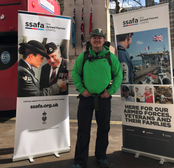 A person in a green jacket stands between two SSAFA charity banners, promoting support for armed forces, veterans, and families transitioning to Civvy Street.
