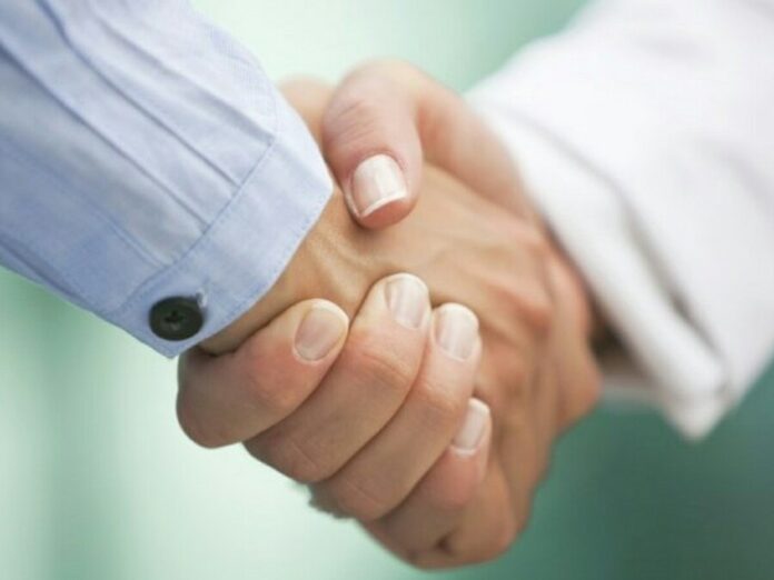 Two people shaking hands, one wearing a blue shirt and the other in white, against a blurred green background, marking the veteran's transition to Civvy Street.