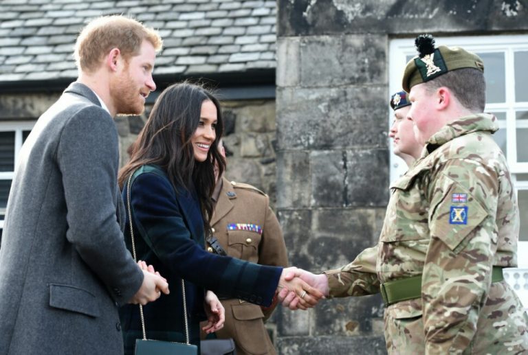 A man and a woman greet uniformed soldiers outdoors, with a brick building in the background, celebrating their successful resettlement from military service to Civvy Street.