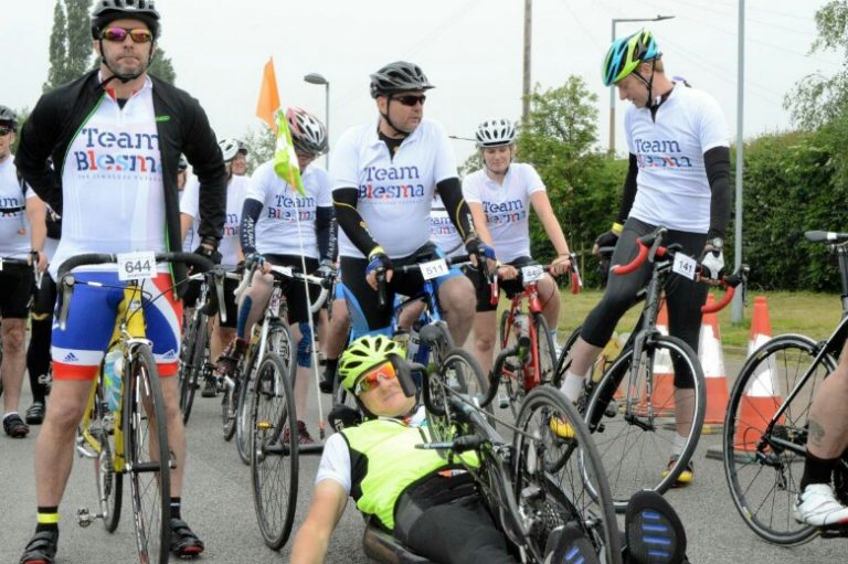 Veterans in "Team Blesma" shirts gather at the starting line, highlighting a journey beyond Civvy Street. In the foreground, an individual on a recumbent bike symbolizes resettlement through cycling camaraderie.