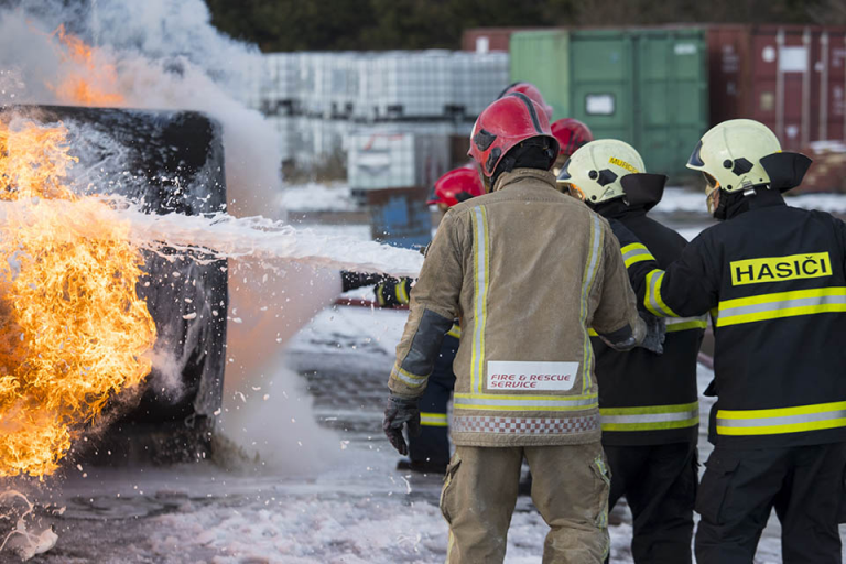 Veteran firefighters in protective gear expertly extinguish a fire with foam, showcasing their skill and dedication long after resettlement into Civvy Street.