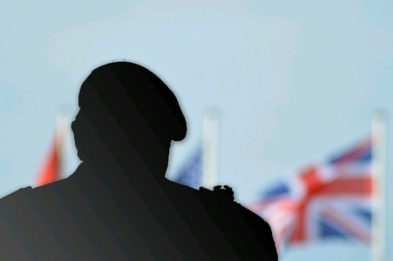 Silhouette of a veteran in a beret against a backdrop of blurred flags, including the Union Jack and the American flag, symbolizing their transition to Civvy Street.