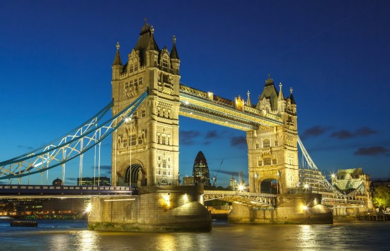 Night view of Tower Bridge in London, its lights twinkling like stars against a dark blue sky. The city skyline looms in the background, reminiscent of a veteran finding their path on Civvy Street.