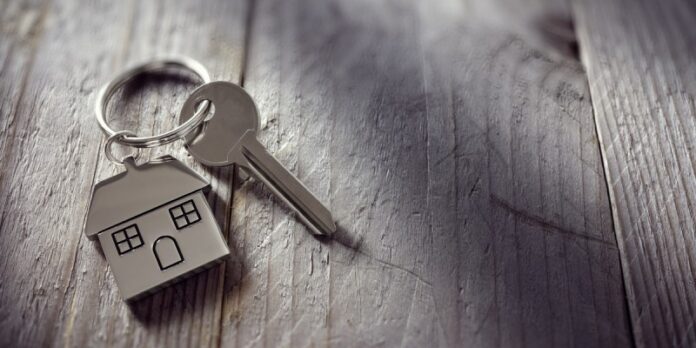 A key with a house-shaped keychain rests on a wooden surface, ready for its new mission in resettlement—its next adventure akin to that of an Army veteran transitioning from service to civilian life.