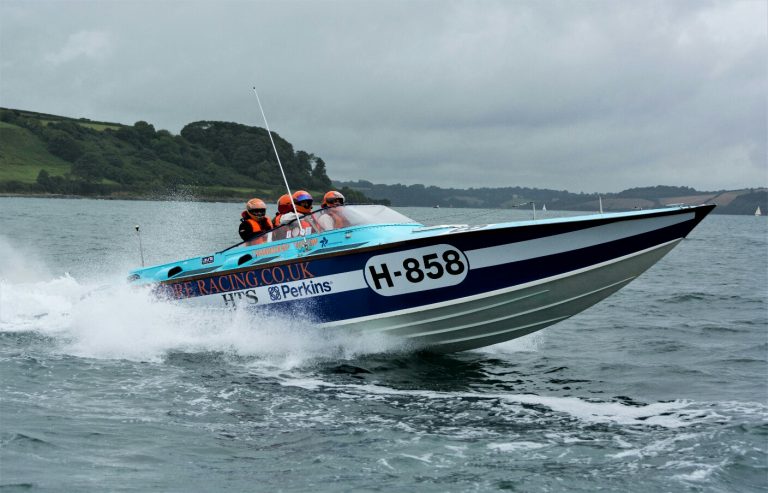 A veteran navigates the speedboat labeled H-858 as it races through the water, with three helmeted passengers onboard.