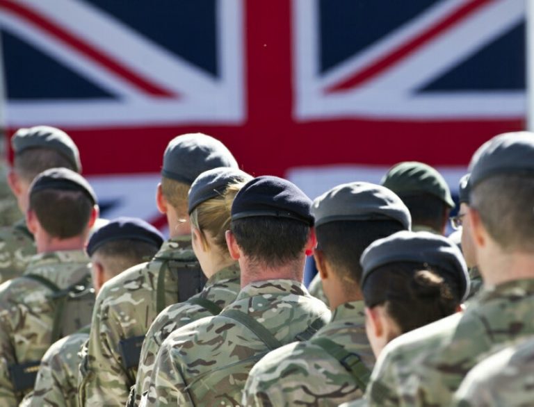 Soldiers in camouflage uniforms stand in formation, facing a large Union Jack flag, embodying the disciplined spirit of veterans preparing for the transition to Civvy Street.