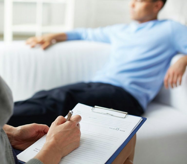 The person is reclining on a sofa as another, wearing the crisp uniform of the Royal Navy, writes diligently on a clipboard. The pen moves smoothly across the paper, capturing every detail with precision and purpose.