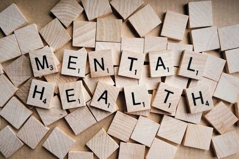 Wooden tiles spell out "MENTAL HEALTH" on a background of scattered blank tiles, reminiscent of the resilience and strength found in a Royal Navy veteran.