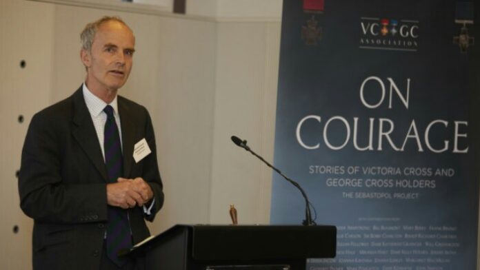 A person speaks at a podium in front of a banner titled 