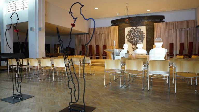 A church interior featuring empty wooden chairs, soldier silhouettes reminiscent of a veteran's devotion, and a central altar with a cross.
