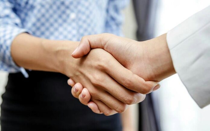 Two individuals shaking hands in a professional setting, as a veteran transitions into a new role, reflecting the resettlement process with mutual respect and understanding.