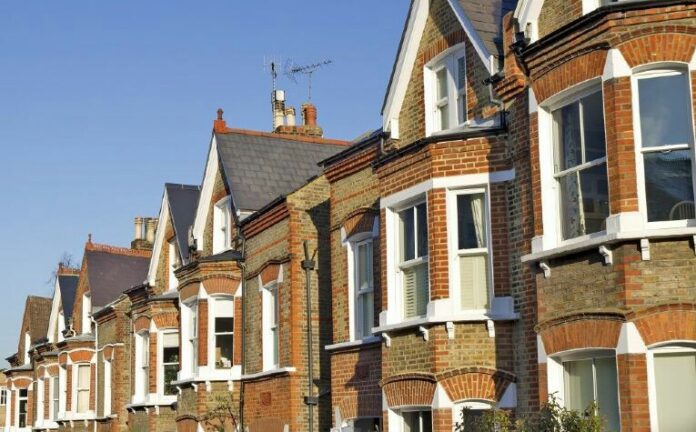 A row of traditional brick terraced houses, reminiscent of those often used in Royal Navy resettlement neighborhoods, stands proudly with gabled roofs, chimneys, and bay windows under a clear blue sky.