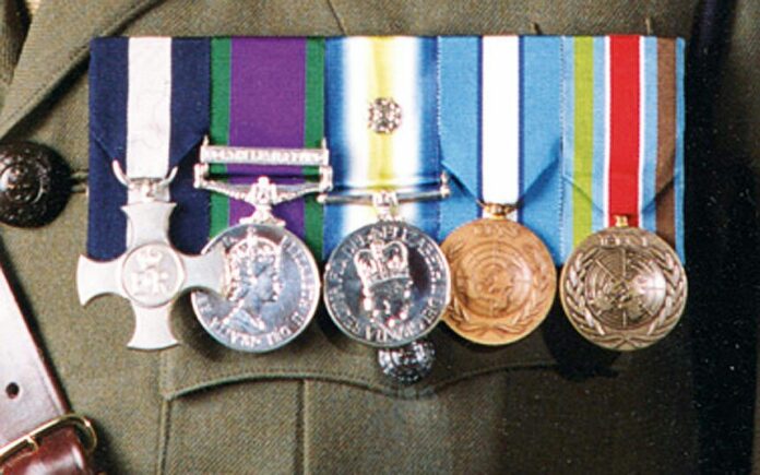 Five military medals displayed on a uniform, featuring ribbons and emblems that reflect years of dedicated service in the Royal Navy.