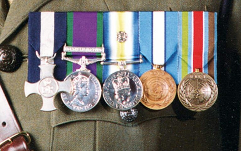 Five military medals displayed on a uniform, featuring ribbons and emblems that reflect years of dedicated service in the Royal Navy.