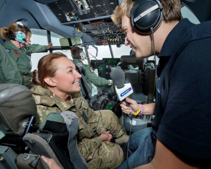 A reporter interviews a seasoned Army pathfinder inside an aircraft cockpit, with other crew members visible in the background.
