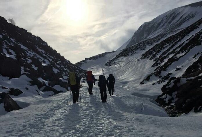 Four pathfinders navigating a snowy mountain landscape under a cloudy sky.