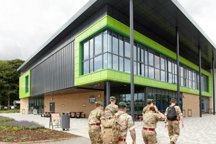 Veteran military personnel walk towards a modern building with green accents and large windows, symbolizing their resettlement journey.