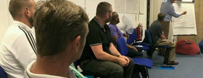 In a classroom filled with attentive pathfinders and resettled veterans, a person stands at the flip chart, guiding them through an insightful session focused on new beginnings and opportunities.
