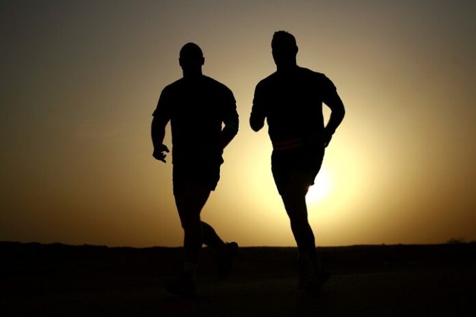 Silhouette of two people jogging at sunset, their forms reminiscent of veteran camaraderie.