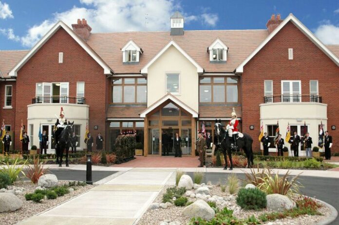 A group of uniformed guards on horseback line the entrance of a brick building with flags, embodying the precision and discipline reminiscent of an army veteran, while a meticulously landscaped path guides visitors.