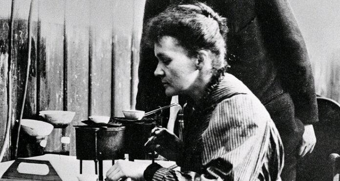 A black and white photo captures a veteran woman working in a laboratory, concentrating on a scientific experiment or equipment.