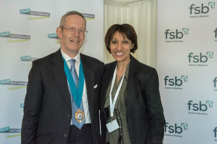 Two people are standing and smiling in front of a backdrop with FSB and 