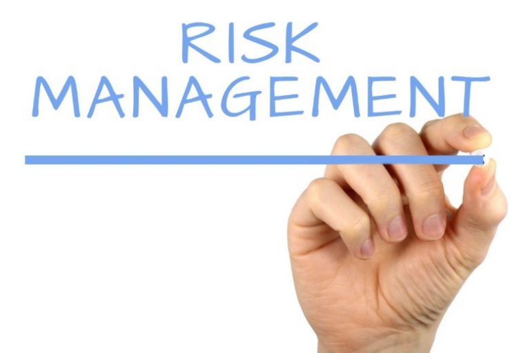 A veteran's hand underlines the words "Risk Management" written in blue uppercase letters.