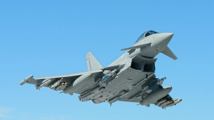 A military jet fighter, like a true pathfinder, soars against the clear blue sky with weapons mounted under its wings.