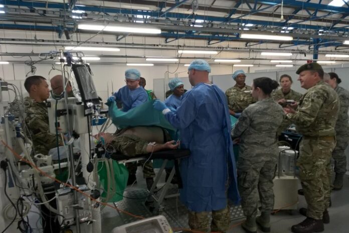 A veteran medical team in military uniforms performs surgery in a hospital setting, with medical equipment and monitors surrounding them, showcasing their pathfinder expertise in critical care.