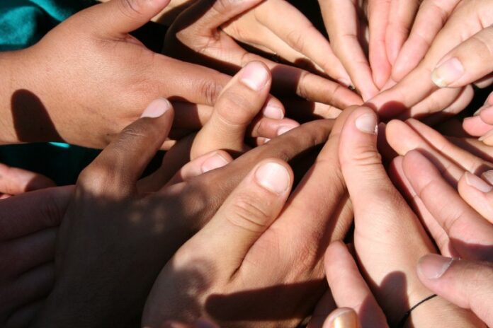 A group of diverse hands forms a circle, thumbs meeting at the center against a textured background, symbolizing support and solidarity for Forces Families.