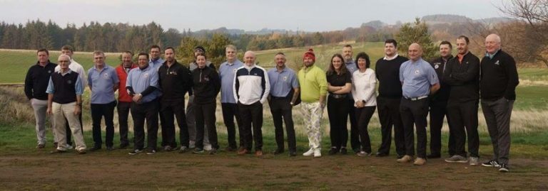 A group of 22 veterans stands in a row on a golf course, surrounded by trees and grassy fields, celebrating camaraderie and recovery in the great outdoors.