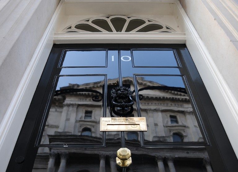 Black door with the number 10 in white, featuring a brass lion door knocker and a mail slot, reflects a building in its glossy surface. This iconic UK entryway symbolizes both tradition and modernity as it opens towards vital discussions on Defence Co-Operation with allies like Poland.