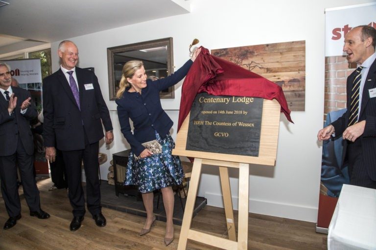 At an indoor event, a woman unveils a plaque honoring the Stoll Award, surrounded by four people in formal attire, celebrating achievements in affordable housing.