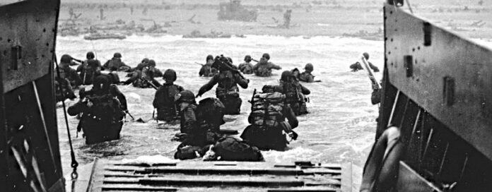 Soldiers wading through water from a landing craft towards the beach during the D-Day anniversary operation.