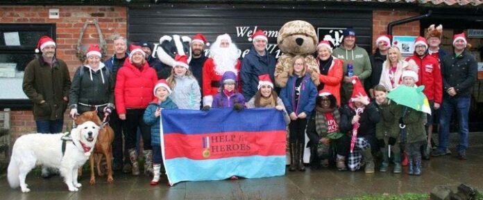 A group of people and dogs donning Santa hats pose with a 