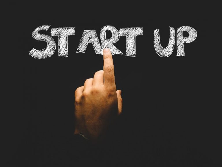A hand points at the words "START UP" written in chalk on a blackboard, evoking the excitement of launching a business start-up after an inspiring workshop.