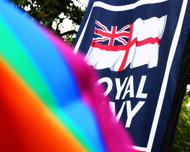 A Royal Navy sign partially obscured by a rainbow-colored flag highlights its recognition as one of the UK's LGBT-friendly employers.