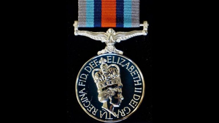A warfare medal showcasing a characterful profile of Elizabeth II, adorned with a striped ribbon on top.