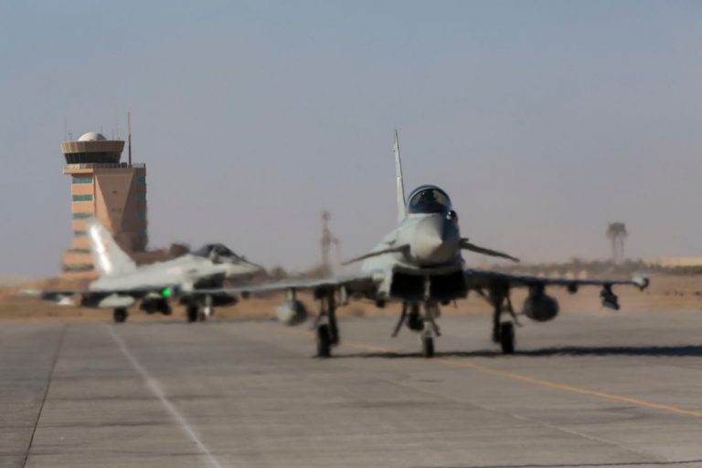 Two Typhoons taxi on a runway, with an air traffic control tower in the background, showcasing their impressive Brimstone Capability.