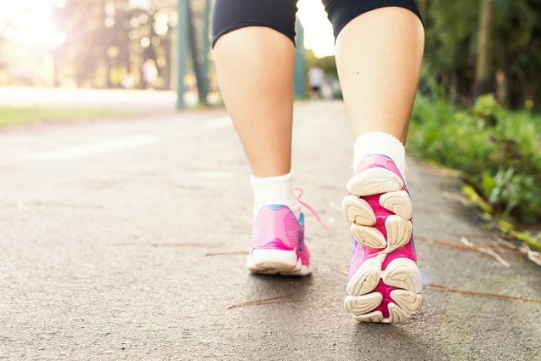 Close-up of a person walking along a path at the National Memorial Arboretum, wearing black leggings, white socks, and pink athletic shoes with white soles as part of a fundraising event.