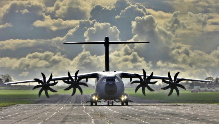 A large RAF military transport aircraft with four propellers is on a runway under a cloudy sky, ready to deliver aid to Mozambique.